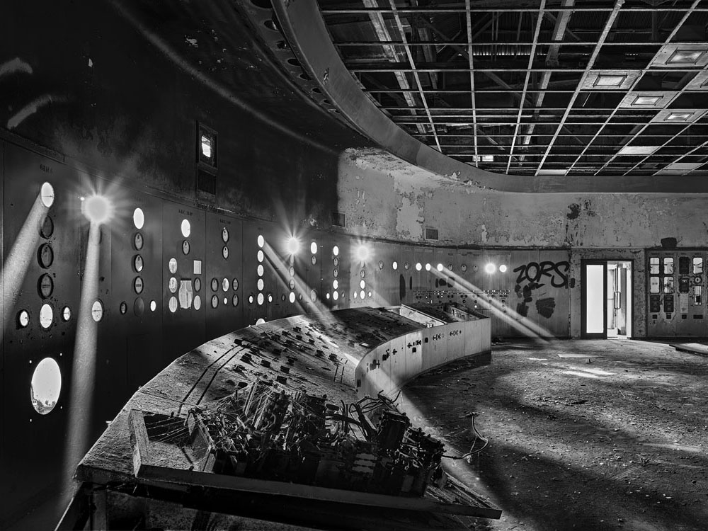 Black and white photo of the Pigeon House control room covered in dust and in ruin.