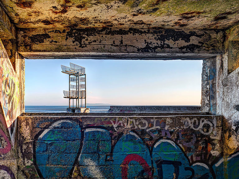 View from inside the abandoned Blackrock Baths in Dublin, looking out through concrete openings to the sea and sky