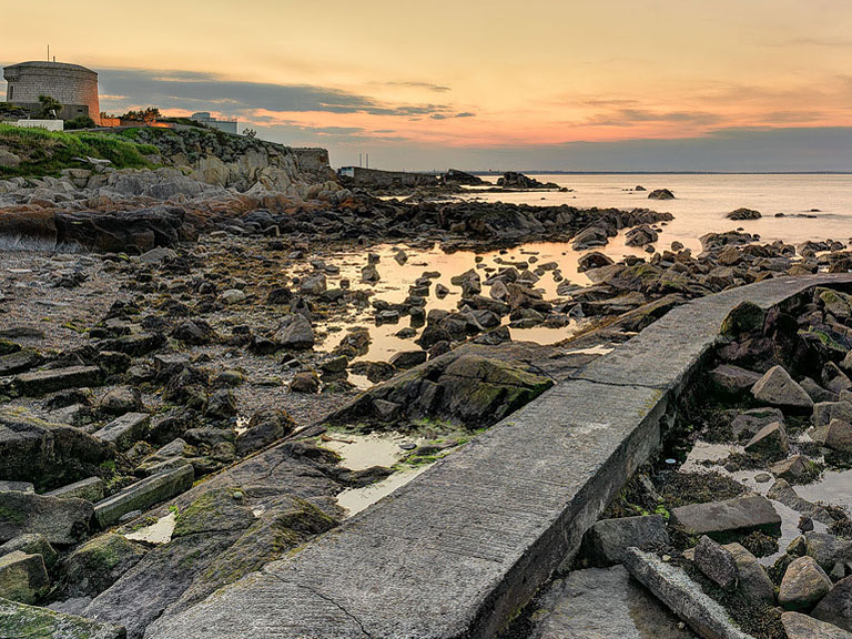 James Joyce Martello Tower at Sandycove on the Dublin coastline with rocks and sea in view