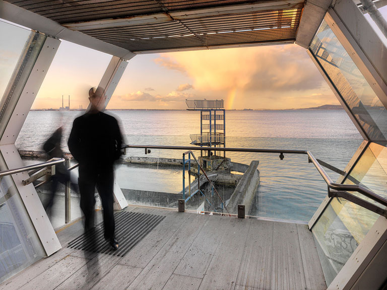 Blackrock Dart Station platforms overlooking Dublin Bay at dusk with the Dublin skyline in the distance