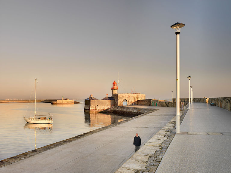 Sunrise light along Dun Laoghaire Pier with a few early walkers and calm Dublin Bay