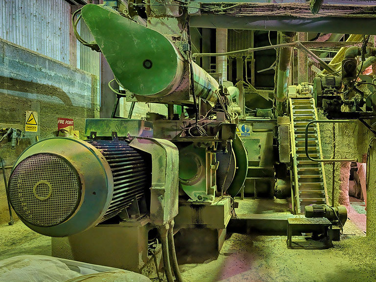 Fine art photograph of an animal feed plant in rural County Meath, with silos, conveyors and sheds set against flat fields and open sky.