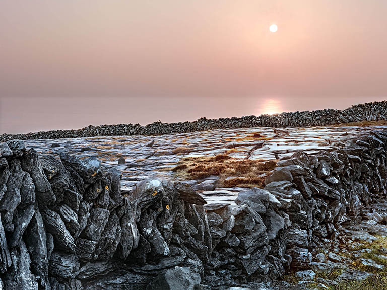 Fine art photograph of a dry stone wall at Black Head in the Burren, with layered limestone blocks, open sky and distant land.