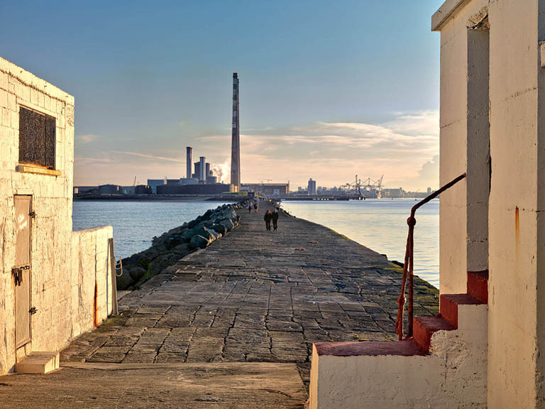 Half Moon Swimming Club House on the South Wall in Ringsend, Dublin, with Poolbeg Power Station and the city skyline in the background.