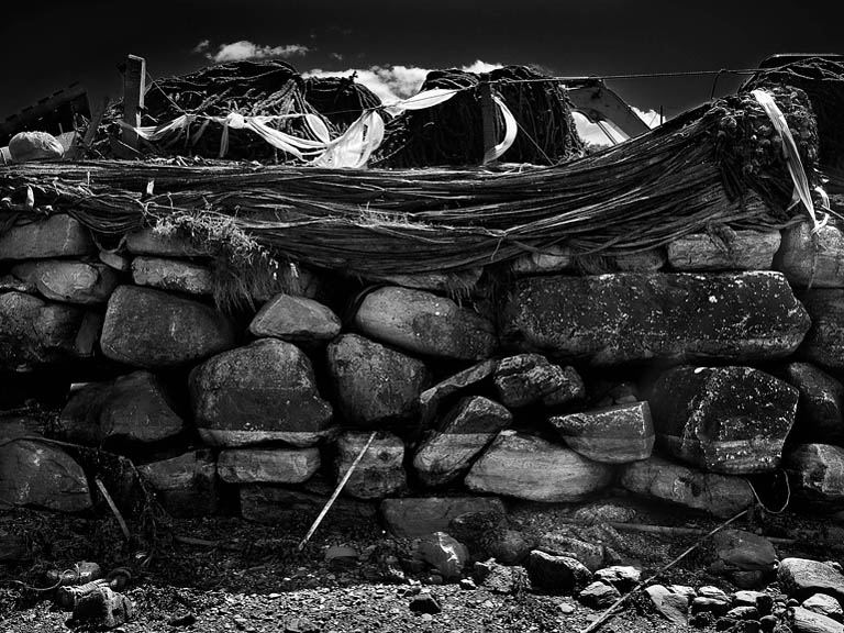 Colourful fishing nets hanging over a weathered stone wall on the Beara Peninsula in West Cork, Ireland.