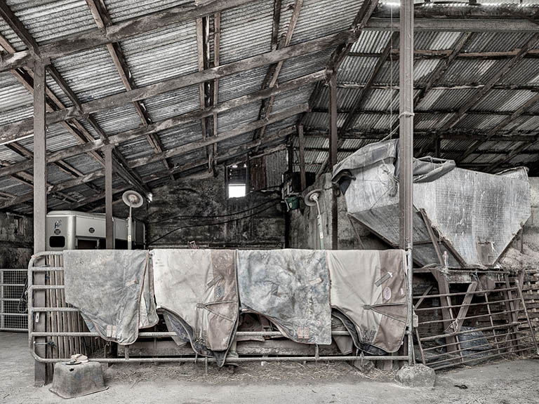 Industrial photograph of worn horse rugs hanging inside a farm shed at a horse stud in County Meath, Ireland