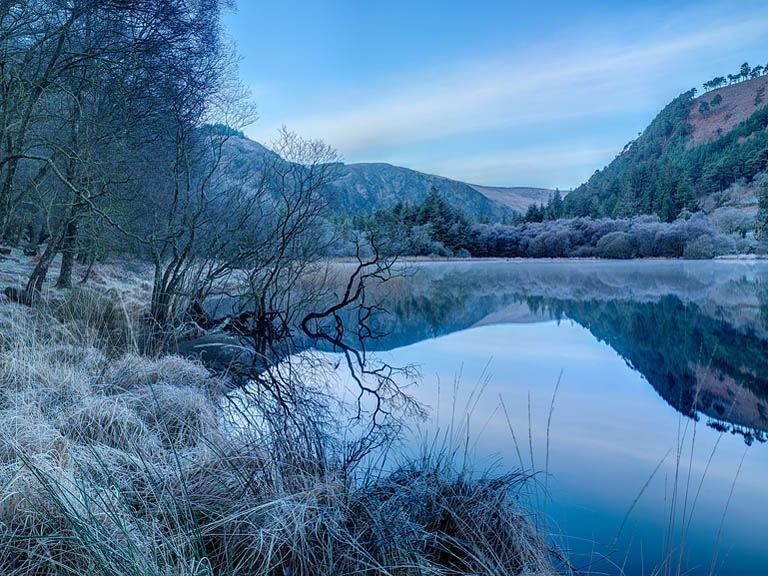 Frosty winter morning at Glendalough Lower Lake in County Wicklow with mountains reflected in still water