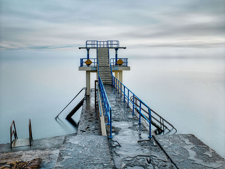 Seascape photograph of Blackrock Diving Tower in Galway with Atlantic swell around the concrete pier