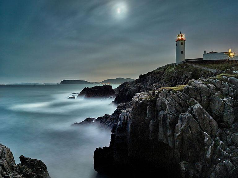 Fine art night photograph of Fanad Lighthouse on the Donegal coast with cliffs and Atlantic in moonlight