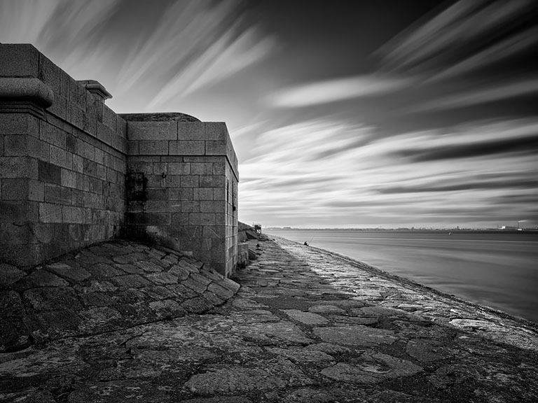 Black and white photograph along Dun Laoghaire West Pier with strong leading lines and Dublin Bay beyond