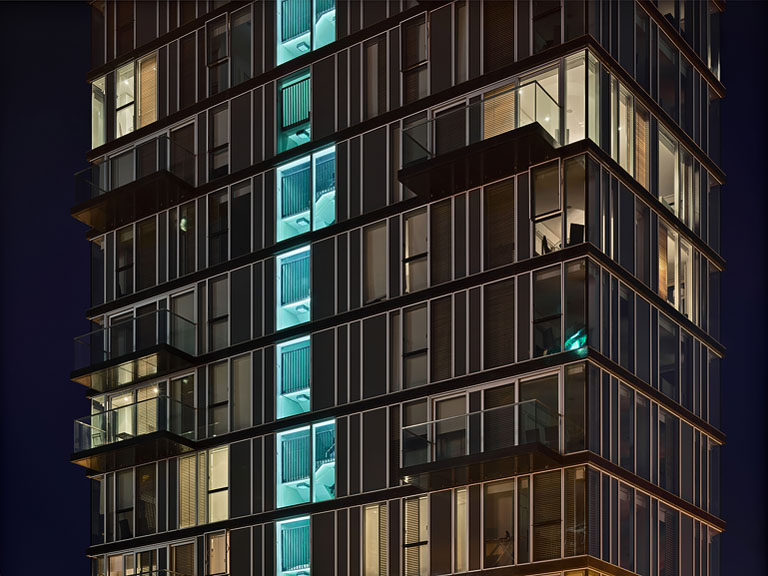 Night photograph of the Alto Vetro building at Grand Canal Dock in Dublin reflected in the water.