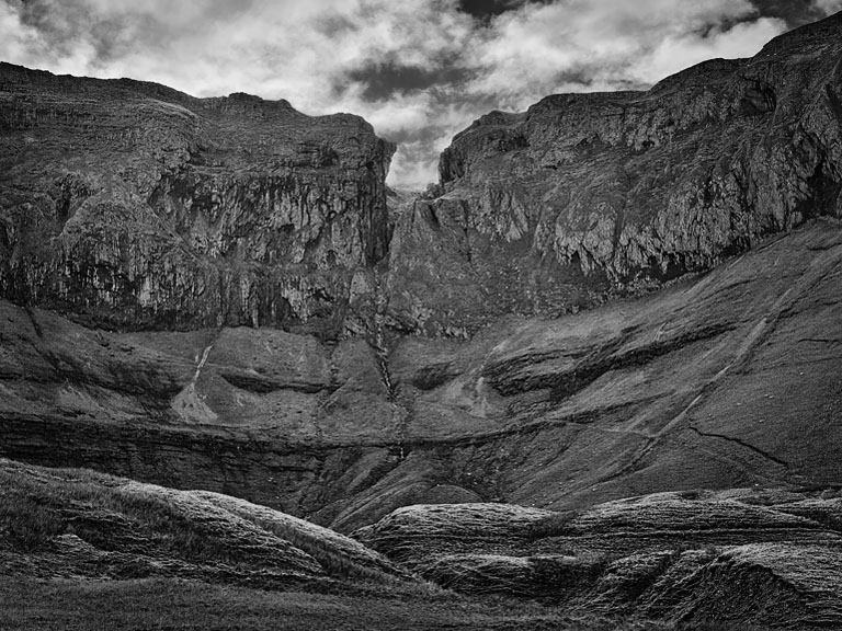 Black and white photograph of the Gleniff Horseshoe cliffs in County Sligo with dramatic bands of sun and shadow.