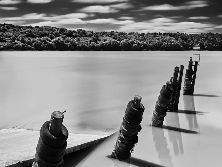 Black and white photograph of Passage East Harbour in County Wexford with pier, water and soft light.