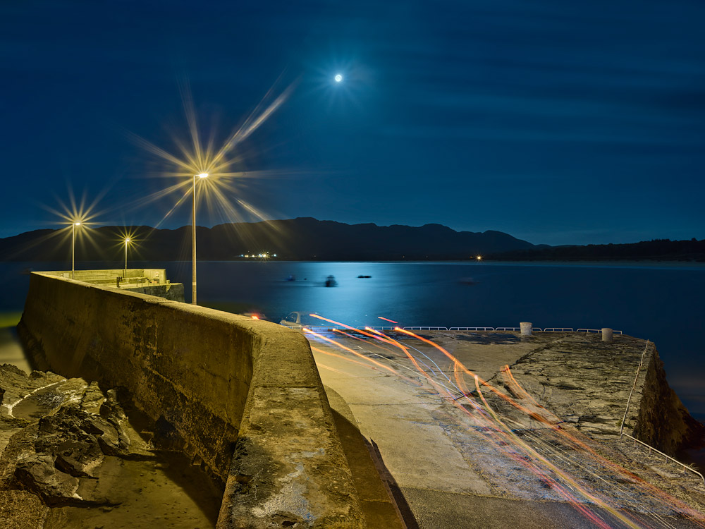 Night photograph of Portsalon Pier at Ballymastocker Beach in County Donegal with the full moon over the water.