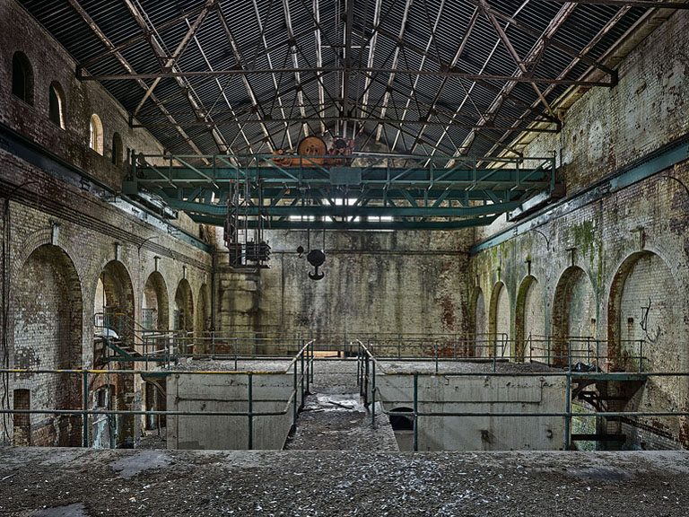 Fine art photograph of the ruined turbine hall at the old Pigeon House Power Station in Dublin with arches and concrete beams.