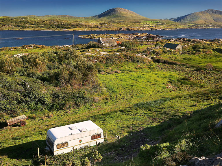 Derelict mobile home and old house above Coulagh Bay on the Beara Peninsula in County Cork