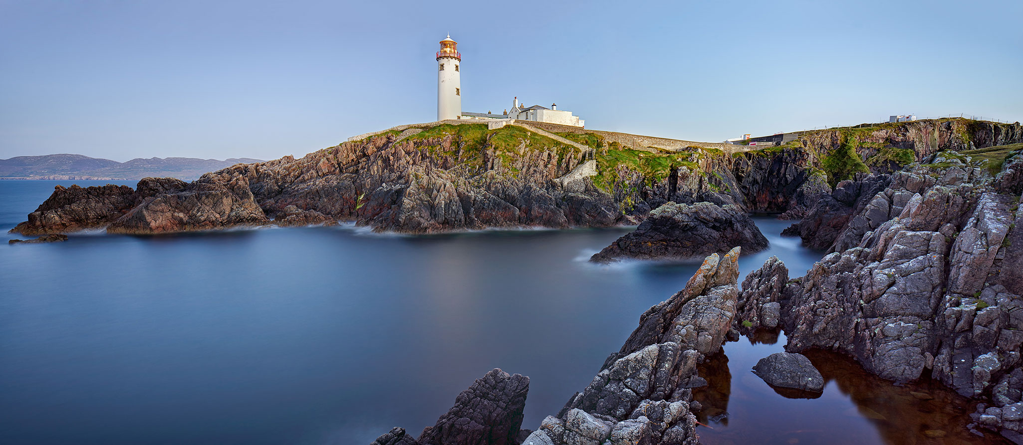 Long exposure photograph of Fanad Head Lighthouse in County Donegal, with smooth still water and soft evening light.