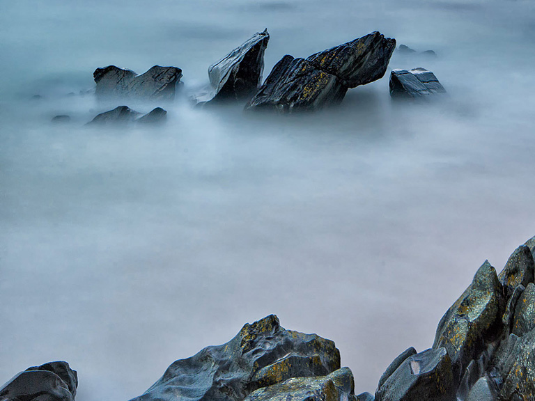 Kylemore Abbey partially framed by trees and woodland, set against the hills of Connemara.