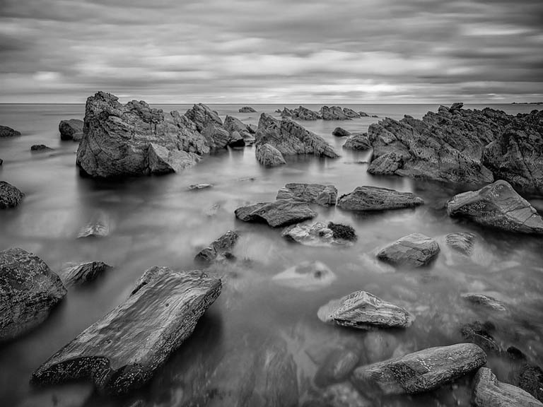 Kylemore Lough in Connemara with calm reflective water, hills and woodland under soft light.