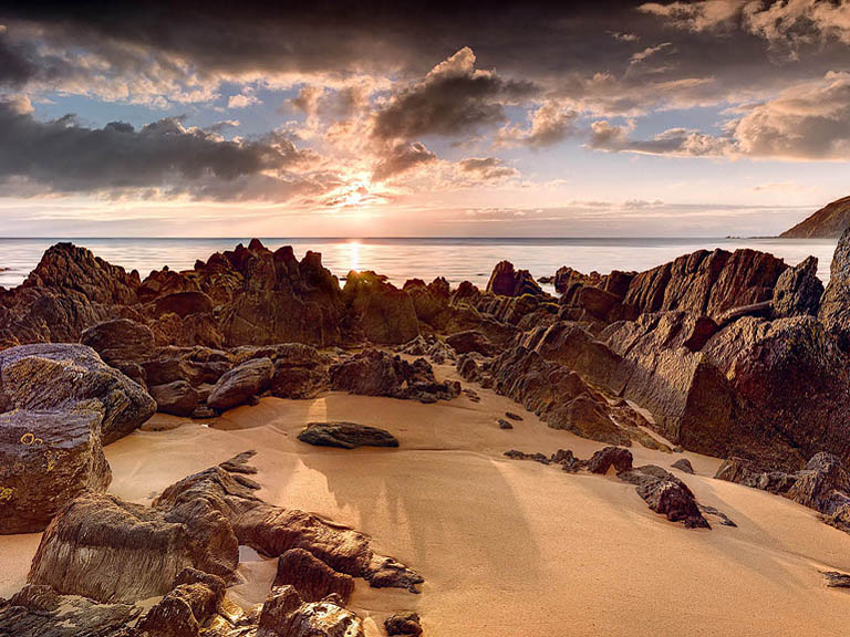 Subtle coastal scene at Loughros Point in County Donegal with low light on rocks, sand and water.