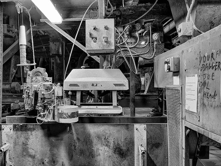 Fine art industrial photograph of staircases, pipes and platforms inside an old animal feed plant, lit by dramatic industrial lighting