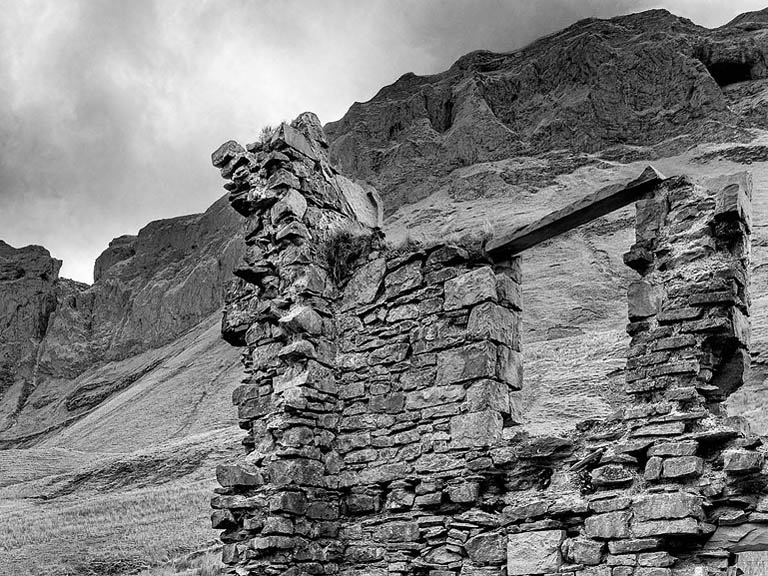 Black and white photograph of the ruined Miner's children school beneath the dramatic cliffs of the Gleniff Horseshoe in County Sligo